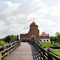Drewniany most prowadzi do ceglanego zamku z czerwoną wieżą. Idealne miejsce na weekendowe wypady, to jedne z fajnych miejsc niedaleko Warszawy na weekend.