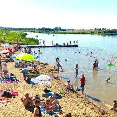 Ludzie odpoczywają na piaszczystej plaży nad rzeką, w krainie dolnej Wisły. Kąpiel, opalanie i relaks w upalny dzień.