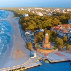 Malownicze polskie wybrzeże miejscowości z latarnią morską, plażą i portem.