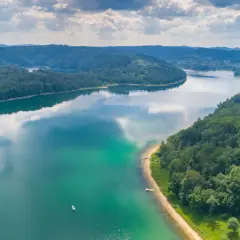 Malownicze jezioro i zalesione wzgórza zapraszają na ferie podkarpackie 2026. Widok z lotu ptaka na spokojną taflę wody i zielone krajobrazy.
