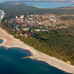 Jarosławiec atrakcje: malownicza plaża z falochronami, las sosnowy i zabudowania kurortu widziane z lotu ptaka.