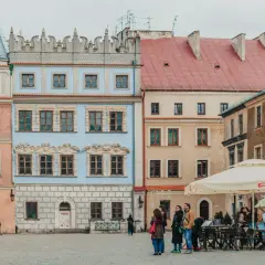 Kolorowe kamienice na rynku, idealne na city break w Europie. Ludzie spacerują, siedzą w kawiarni.