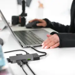 Praca zdalna i turystyka w jednym. Ktoś planuje podróż, przeglądając oferty na laptopie, podłączonym do hubu USB.