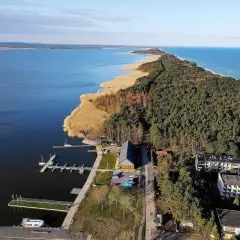 Dąbki atrakcje: malowniczy widok na jezioro, las i morze. Widoczne molo, przystań jachtowa i budynki.