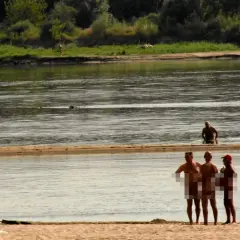 Ludzie opalają się i kąpią na piaszczystej plaży nad rzeką. To popularne miejsce, gdzie można spotkać plażę nudystów.