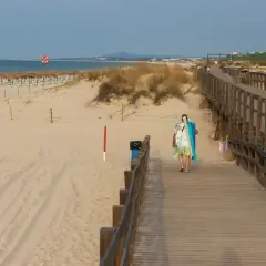 Drewniany deptak prowadzi na piaszczystą plażę. W oddali widać morze i rzędy parasoli. To idealne miejsce na spacer i odkrywanie atrakcji Grzybowa.