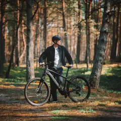 Mężczyzna z rowerem w lesie, gotowy do odkrywania tras rowerowych Łeba.