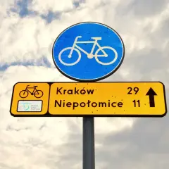 Znak drogowy informuje, że kiedy rowerzysta ma pierwszeństwo, kieruje się na Kraków (29 km) i Niepołomice (11 km).
