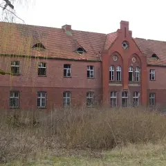 Opuszczony budynek z cegły, zniszczony dach i wybite okna. Miejsce to mogłoby być jednym z nawiedzonych miejsc w Polsce, pełnym mrocznych historii.