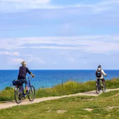 Dwie osoby na rowerach przemierzają malowniczą trasę rowerową R10 nad Bałtykiem.