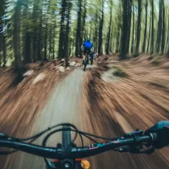 Zjazd rowerowy po leśnym single track glacensis. Widok z perspektywy kierownicy, przed nami inny rowerzysta.