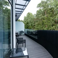 Nowoczesny taras z widokiem na las, idealne miejsce na **długi weekend**. Meble wypoczynkowe i szklane balustrady.