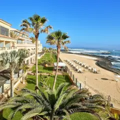 Hotel z widokiem na plażę i ocean. Palmy, leżaki i spokojne morze. Idealne miejsce na Fuerteventurze, gdzie najmniej wieje.