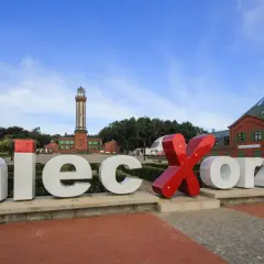 Niesamowite niechorze atrakcje: napis "Niechorze", latarnia morska i ceglane budynki.