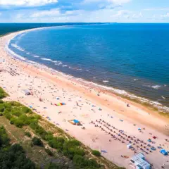 Słoneczne plaże w Polsce tętnią życiem. Tłumy ludzi odpoczywają na piaszczystym brzegu, kąpią się w morzu i cieszą się wakacjami.