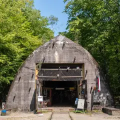 Betonowy bunkier w lesie, jedna z ciekawych województwo łódzkie atrakcje. Wejście otwarte, widać ludzi i ekspozycję.