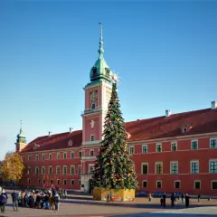 Wspaniała choinka w Warszawie przed Zamkiem Królewskim, ozdobiona kolorowymi lampkami i bombkami, przyciąga tłumy spacerowiczów.