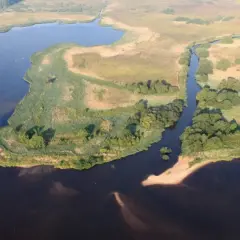 Malownicze krajobrazy pomorza gdańskiego: jezioro, kanał, trzciny i piaszczyste brzegi.