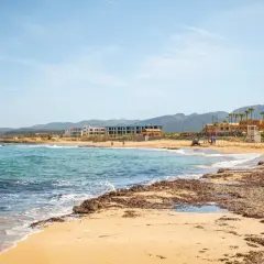 Piękna plaża z turkusową wodą i hotelami w tle. Idealne miejsce, gdzie na Krecie można odpocząć.