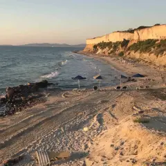 Plaża z klifem w tle, morze i leżaki. Czy warto tu przyjechać? Zdecydowanie tak!