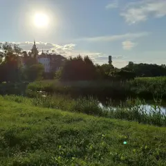Słoneczny dzień nad rzeką w Supraślu. Idealne miejsce na weekendowe atrakcje, spacer po brukowanej ścieżce wśród zieleni i podziwianie klasztoru.