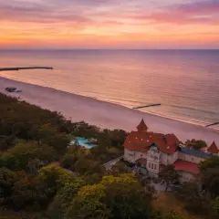 Zachód słońca nad Bałtykiem, idealne miejsce, gdzie na wakacje w Polsce. Piękna plaża, las i zabytkowy budynek z basenem.