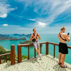 Widok na wyspy w **Angthong National Marine Park**. Dwóch mężczyzn robi zdjęcia telefonami z tarasu widokowego.