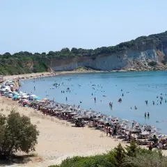 Piękna plaża na wyspie Kos, pełna ludzi kąpiących się i opalających. Uważaj na słońce i tłumy, by w pełni cieszyć się wakacjami.