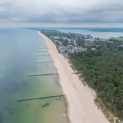 Mielno atrakcje: szeroka plaża, las sosnowy i zabudowania kurortu nad Bałtykiem. Widok z lotu ptaka na wybrzeże.