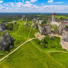 Malowniczy krajobrazowy park orlich gniazd z ruinami zamków na wapiennych skałach, zielone wzgórza i błękitne niebo.