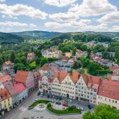 Urokliwy rynek w Dusznikach Zdroju, otoczony kolorowymi kamieniczkami, zachęca do odkrywania lokalnych atrakcji.
