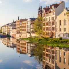 Nad Odrą w Opolu, zabytkowe kamienice odbijają się w spokojnej wodzie. To piękne opole atrakcje, które warto zobaczyć.