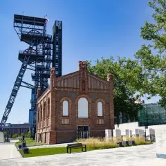 Wieża szybu kopalnianego i ceglany budynek tworzą ciekawe miejsca do 50 km od Katowic. Teren z zielenią i ławką zaprasza do zwiedzania.