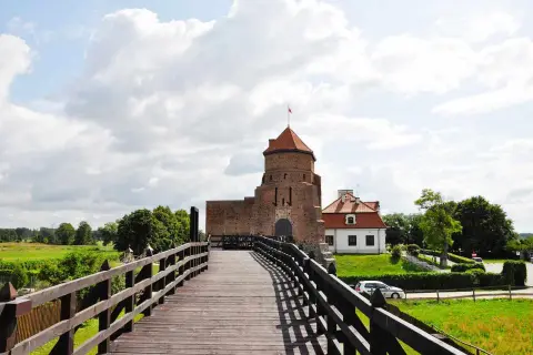 Drewniany most prowadzi do ceglanego zamku z czerwoną wieżą. Idealne miejsce na weekendowe wypady, to jedne z fajnych miejsc niedaleko Warszawy na weekend.
