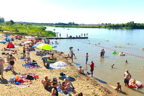 Ludzie odpoczywają na piaszczystej plaży nad rzeką, w krainie dolnej Wisły. Kąpiel, opalanie i relaks w upalny dzień.