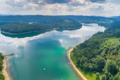 Malownicze jezioro i zalesione wzgórza zapraszają na ferie podkarpackie 2026. Widok z lotu ptaka na spokojną taflę wody i zielone krajobrazy.