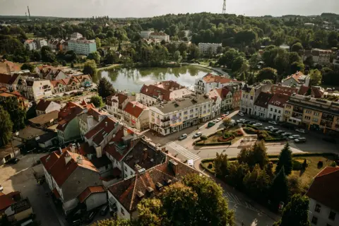 Widok z lotu ptaka na urokliwe Mrągowo. Jezioro, kolorowe kamienice i zielone drzewa tworzą malowniczy krajobraz. Odkryj mrągowo atrakcje!