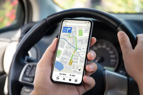 Ręce kierowcy trzymają telefon z nawigacją, co jest niebezpiecznym korzystaniem z telefonu podczas jazdy rowerem.