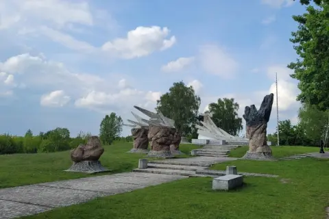 Pomnik w Białymstoku, jedna z jego atrakcji, z kamiennymi rzeźbami i betonowymi formami na tle zieleni i błękitnego nieba.