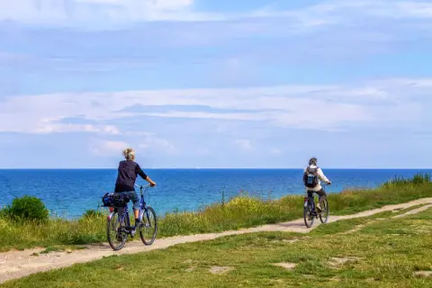 Dwie osoby na rowerach przemierzają malowniczą trasę rowerową R10 nad Bałtykiem.