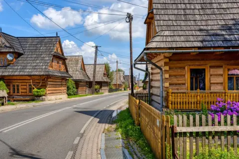 Drewniane domy w stylu zakopiańskim wzdłuż drogi. Wiele atrakcji w okolicy Chochołowa czeka na odkrycie.