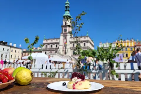 Słodki przysmak na talerzyku, w tle Ratusz i kolorowe kamienice – idealne miejsce na festiwal wina Zamość.