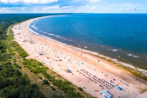 Słoneczne plaże w Polsce tętnią życiem. Tłumy ludzi odpoczywają na piaszczystym brzegu, kąpią się w morzu i cieszą się wakacjami.