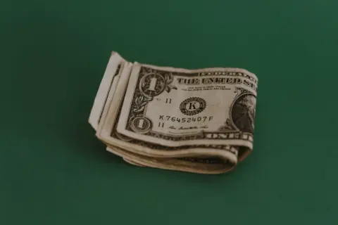 Kilka banknotów jednodolarowych leży na zielonym tle. Zastanawiasz się, jaki napiwek w restauracji zostawić?
