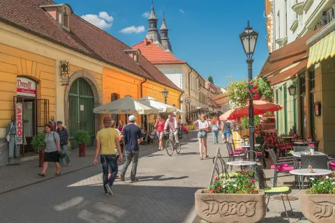 Tętniąca życiem ulica w Egerze, Węgry. Ludzie spacerują, jeżdżą na rowerze, siedzą w kawiarniach. Węgry atrakcje turystyczne.