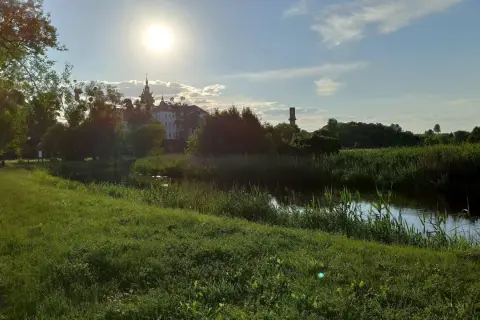 Słoneczny dzień nad rzeką w Supraślu. Idealne miejsce na weekendowe atrakcje, spacer po brukowanej ścieżce wśród zieleni i podziwianie klasztoru.