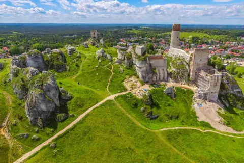 Malowniczy krajobrazowy park orlich gniazd z ruinami zamków na wapiennych skałach, zielone wzgórza i błękitne niebo.
