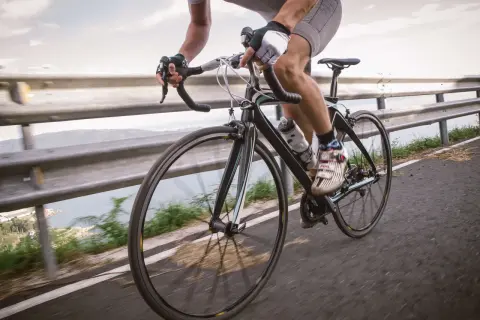 Rowerzysta w rękawiczkach i spodenkach ściga się po drodze. Czy rowerzysta może wyprzedzać z prawej strony? To zależy od przepisów.