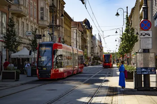 Czerwony tramwaj na ulicy w Katowicach, jedno z fajnych miejsc w Katowicach. W tle kolejne tramwaje i kamienice.