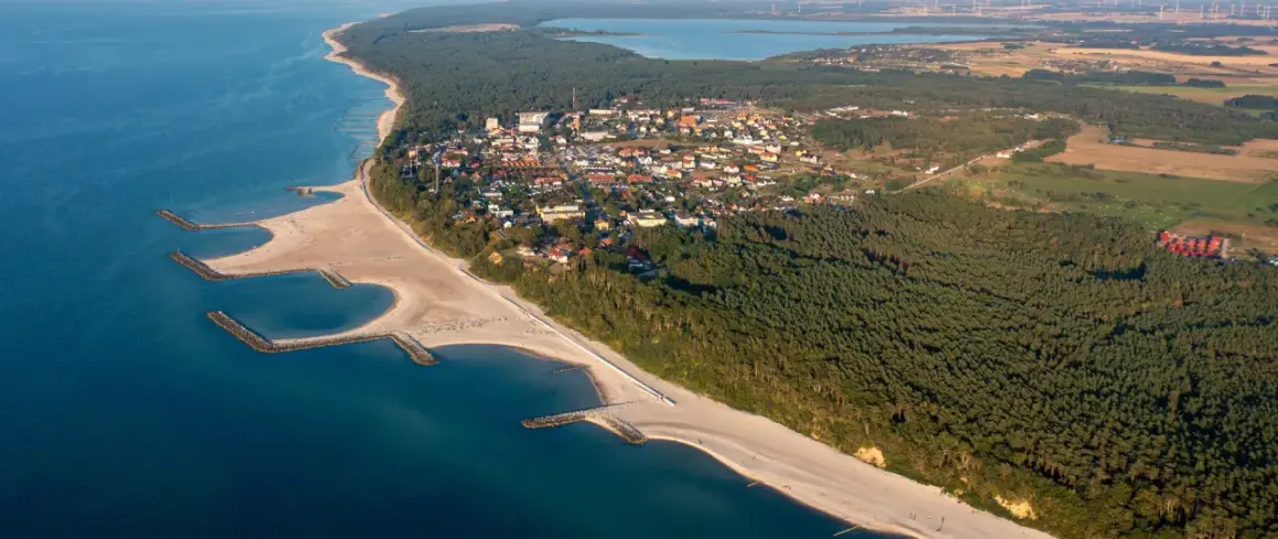 Jarosławiec atrakcje: malownicza plaża z falochronami, las sosnowy i zabudowania kurortu widziane z lotu ptaka.